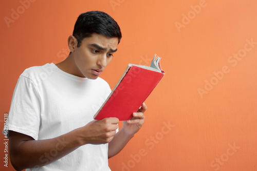 Boy reading a book with confused face 