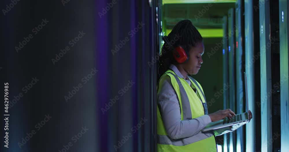 African american female computer technician using laptop working in business server room