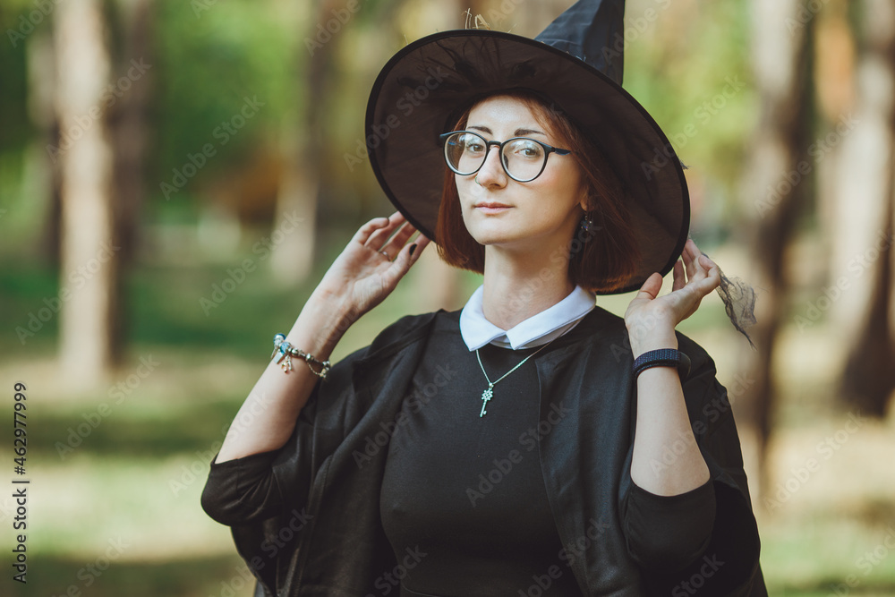 Halloween Witch. Portrait of a girl in a hat and a witch costume in the forest. Ready for trick or treat holiday