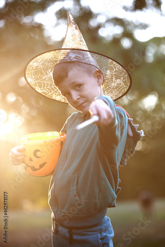Cute little toddler boy playing wizard with a wand on halloween, autumn forest