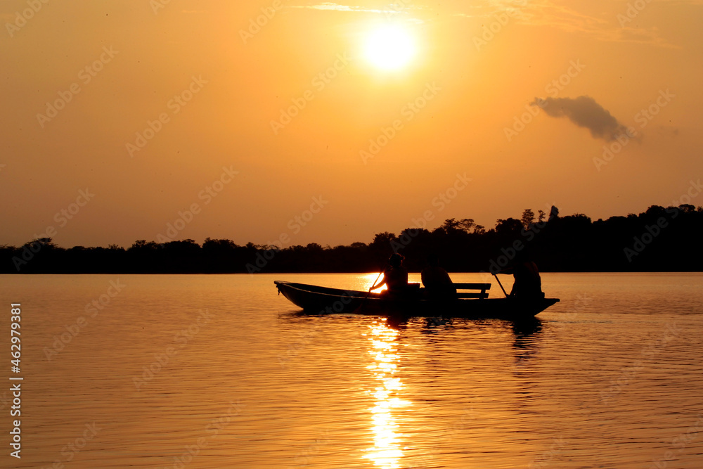 Silhouette of a group of Fishermen Fishing on a Smal Boat at Sunset