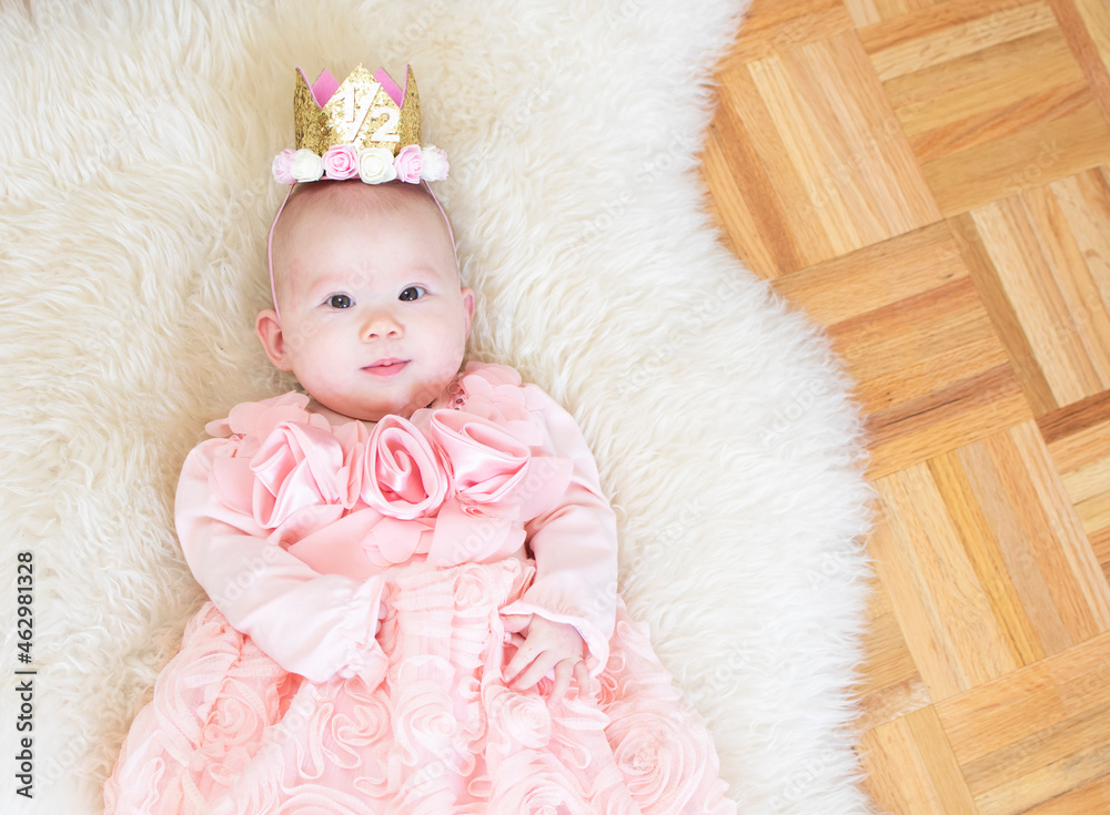 6-month-old baby girl. Half birthday. Happy birthday, princess. Cute caucasian baby girl in a pink dress. Tiara baby
