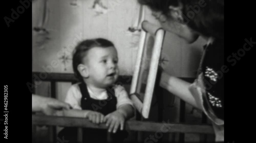 Baby Kisses GI Dads Picture 1952 - A baby in the crib kisses a portrait of his father dressed in uniform.  photo