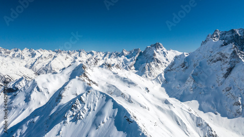 Caucasus Mountains, Panoramic view of the ski slope with the mountains Belalakaya, Sofrudzhu and Sulakhat on the horizon in winter day. Dombai ski resort, Western Caucasus, Karachai-Cherkess, Russia. © evgenii