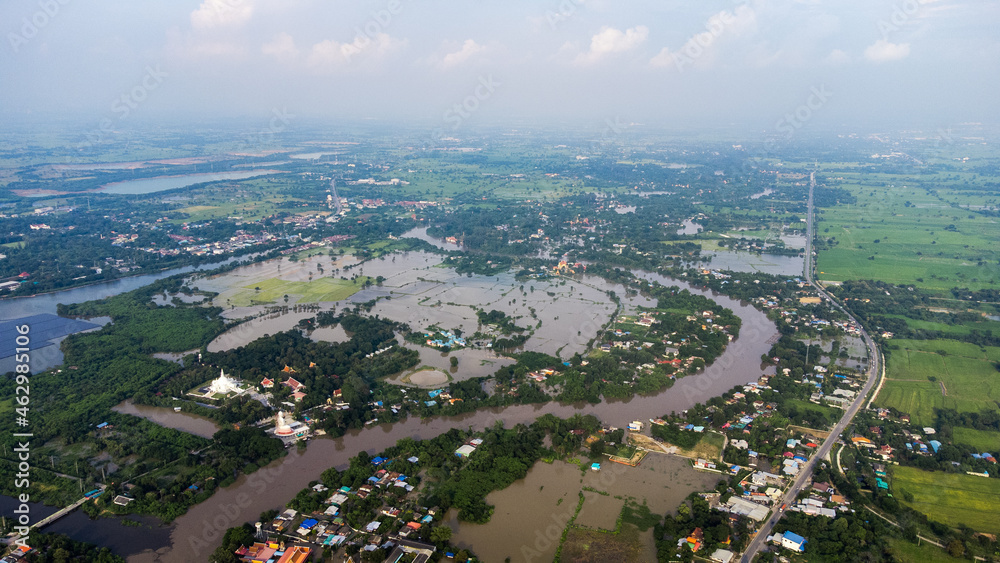 Fototapeta premium Flood waters overtake a house and rice field at Central of Thailand in 2021. Many buildings are submerged in water. Photo disaster from above view by drone