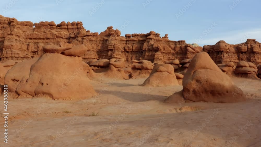 Gorgeous dolly in aerial drone shot of the beautiful Goblin Valley Utah State Park approaching strange mushroom rock formations with red hoodoo formations in the background on a warm sunny summer day. Gorgeous dolly in aerial drone shot of the beautiful Goblin Valley Utah State Park approaching strange mushroom rock formations with red hoodoo formations in the background on a warm sunny summer day.