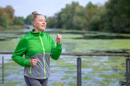 Fit energetic woman working out jogging along a river © michaelheim