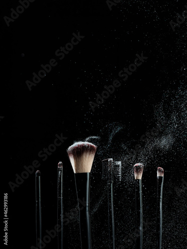 Black cosmetic makeup brush on a black background 