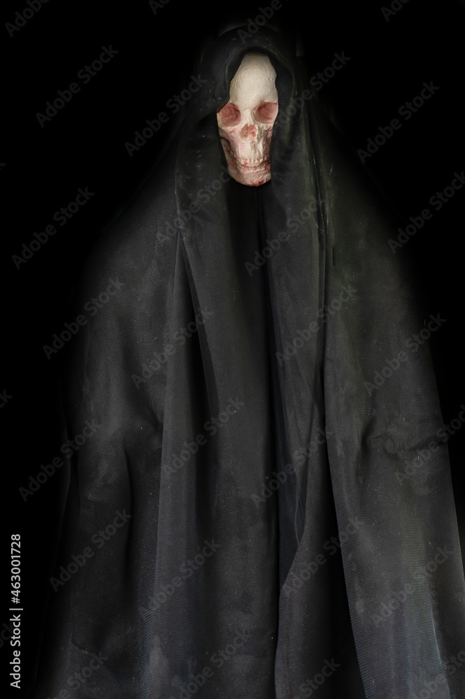 human skull in black hood in the dark