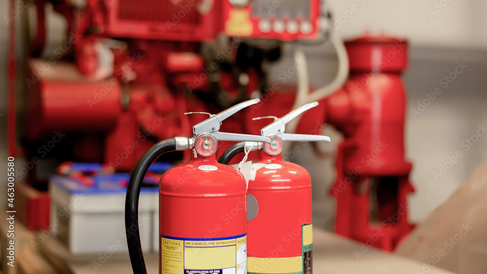 The red fire extinguisher is ready for use in case of an indoor fire emergency. The red fire extinguisher is ready for use in case of an indoor fire emergency.