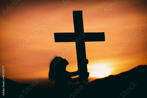 young girl looking at the cross with hope in god at sunset, christian silhouette concept.
