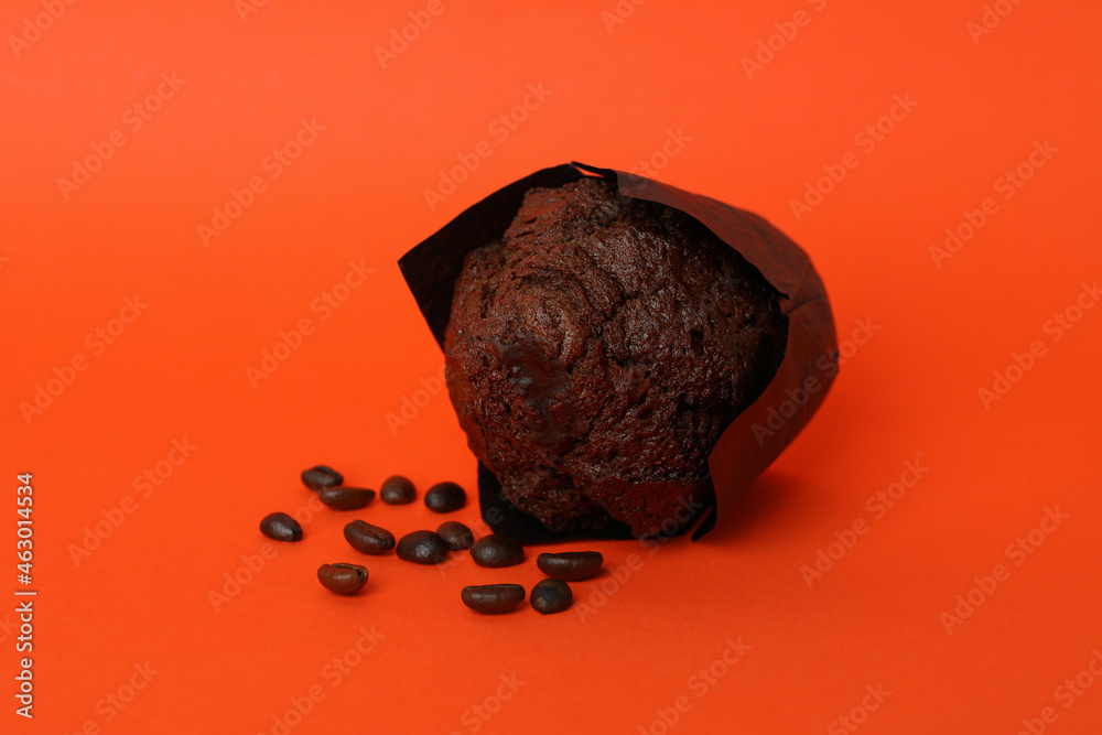 Naklejka premium Chocolate muffin with coffee seeds on orange background