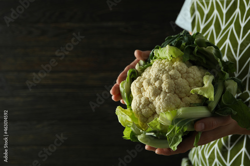Woman in apron holds fresh cauliflower, space for text