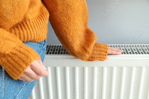 Concept of heating season with girl sitting on radiator photo