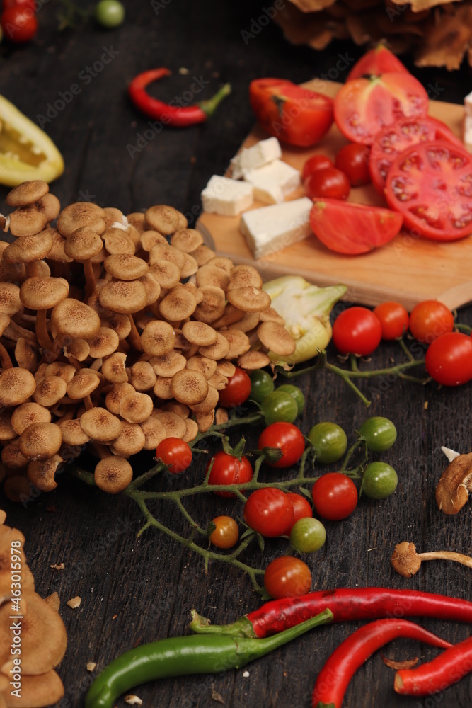 Food photography, plating of cherry tomatoes, mushrooms, peppers and sliced ​​cheese, placed on rustic wooden table