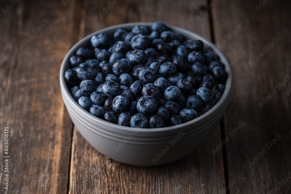 Blueberries in ceramic bowl on rustic wooden background. Selective focus. Shallow depth of field. Blueberries in ceramic bowl on rustic wooden background. Selective focus. Shallow depth of field.