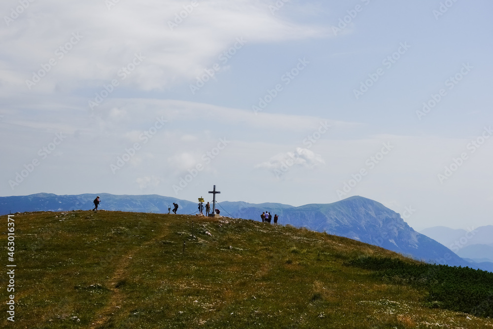 hikers near a summit cross on the top from a mountain