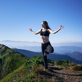 Full length of fit woman in sportswear balancing on one leg and doing Gyan mudra hand gesture while practicing yoga outdoors. Athletic young woman doing yoga exercise in mountains.