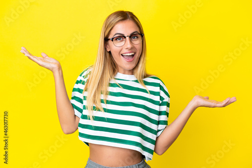 Blonde Uruguayan girl isolated on yellow background with shocked facial expression