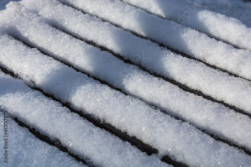 Fresh white snow lies on the bench. Snowy texture