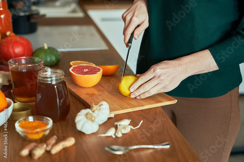 Unrecognizable woman cutting lemon for winter tea