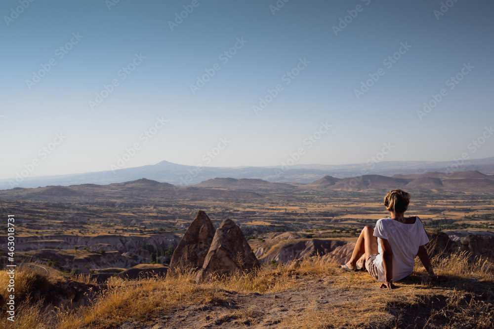 Fototapeta premium rear view of blonde Caucasian young woman admiring landscape in Cappadocia