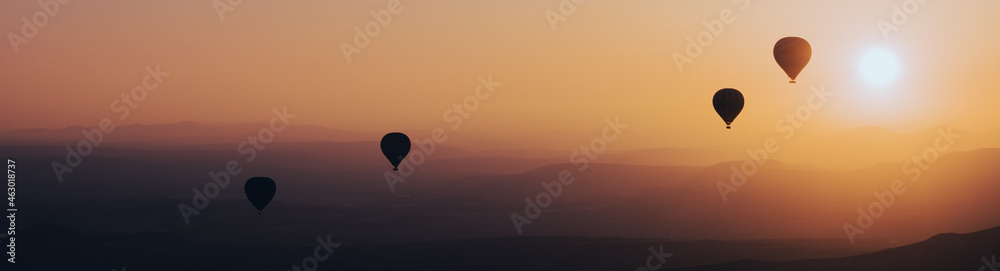 Naklejka premium hot air balloon silhouette with sun rising over the mountains