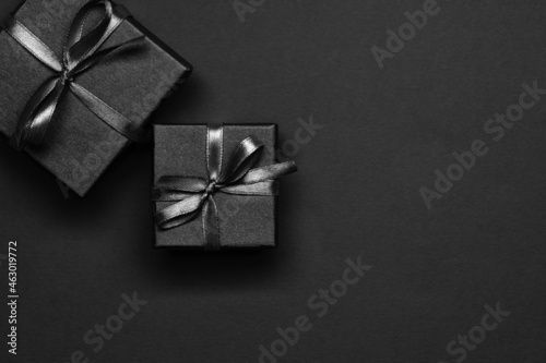 Black gift boxes tied with black ribbons on a black background.