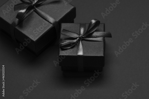 Black gift boxes tied with black ribbons on a black background.