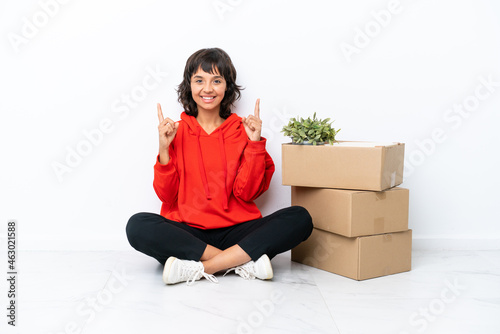 Young girl moving in new home among boxes isolated on white background pointing up a great idea