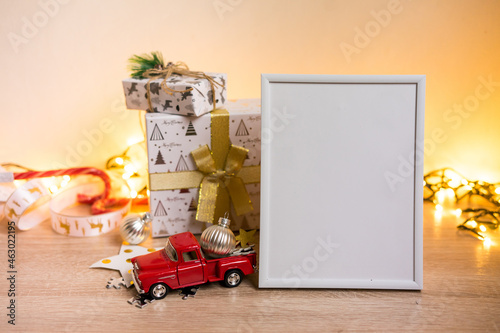 Portrait white picture frame mockup with christmas gifts, boken lights photo