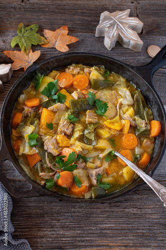 Stew with vegetables, pumpkin, potatoes and pork meat in a cast iron skillet
