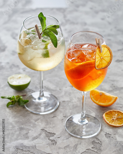 two cocktails with lime and ice over grey background