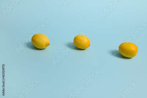 Bright yellow lemons on blue pastel background. Minimalistic food composition with copy space for advertisement
