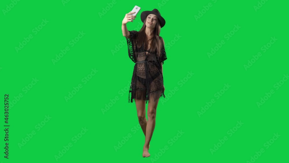 Pretty influencer summer girl in tunic walking and vlogging with smart phone. Full body on green screen chroma key background Pretty influencer summer girl in tunic walking and vlogging with smart phone. Full body on green screen chroma key background