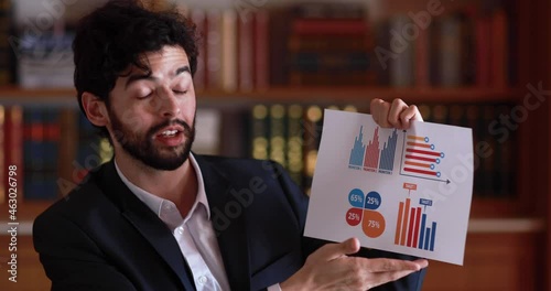 Confident executive director caucasian businessman in suit holding paper of graph and charts diagram and explain to web camera in online meeting with specialist action. Remote gob assignment concept. photo