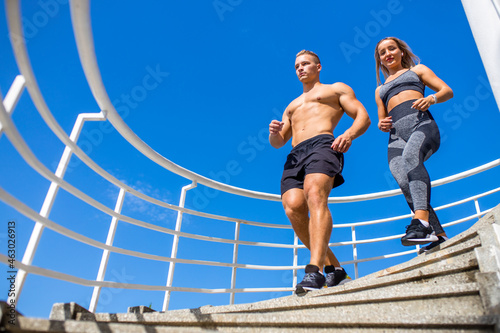 young couple in sport clothing doing stretching exercises together outdoor in summer beach tropics