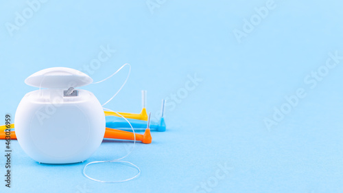 Dental floss and interdental brush angles on blue background, copy space