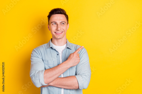 Portrait of attractive cheerful content guy demonstrating copy blank place space ad isolated over bright yellow color background © deagreez