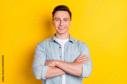 Photo of young cool confident smiling charismatic businessman with folded hands isolated on yellow bright background