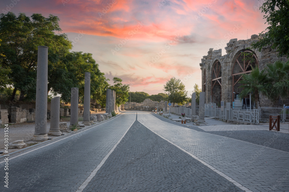 ancient theater exterior, Antalya Side. The paved road, the cloudy sunset sky, the pillars and the exterior of the theater. No people