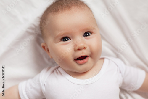 portrait of a cute smiling newborn baby in a white bodysuit on a white background close up. products for children. concept of happy childhood and motherhood. child care. High quality photo