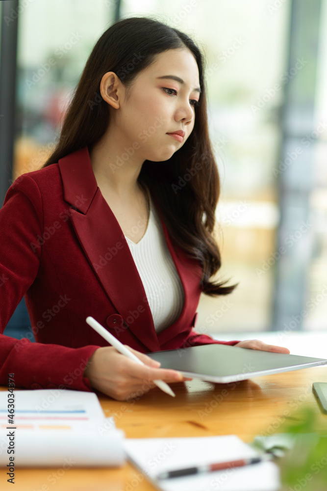 Unhappy young asian businesswoman working on tablet computer in the office Unhappy young asian businesswoman working on tablet computer in the office