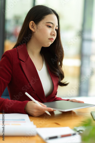 Unhappy young asian businesswoman working on tablet computer in the office