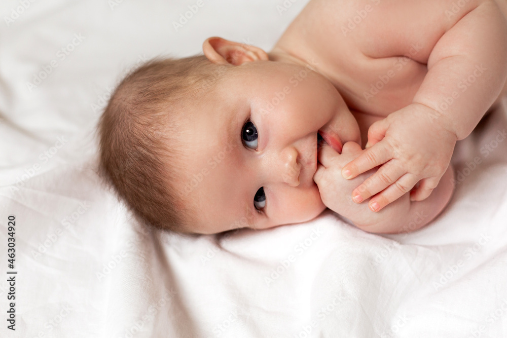 cute thoughtful newborn baby is lying on its side on a white bed. products for children. concept of a happy childhood and motherhood. child care. space for text. High quality photo cute thoughtful newborn baby is lying on its side on a white bed. products for children. concept of a happy childhood and motherhood. child care. space for text. High quality photo
