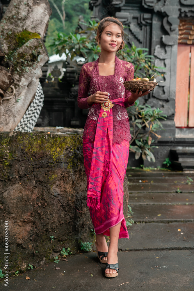 Beautiful Asian girl dressed in traditional Balinese kebaya costume outside a Hindu temple, styles Bali, Indonesia. Beautiful Asian girl dressed in traditional Balinese kebaya costume outside a Hindu temple, styles Bali, Indonesia.