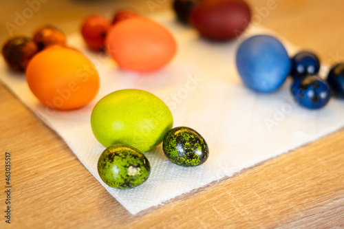 Freshly painted green, blue, red and orange Easter chicken and quail eggs lie in the kitchen