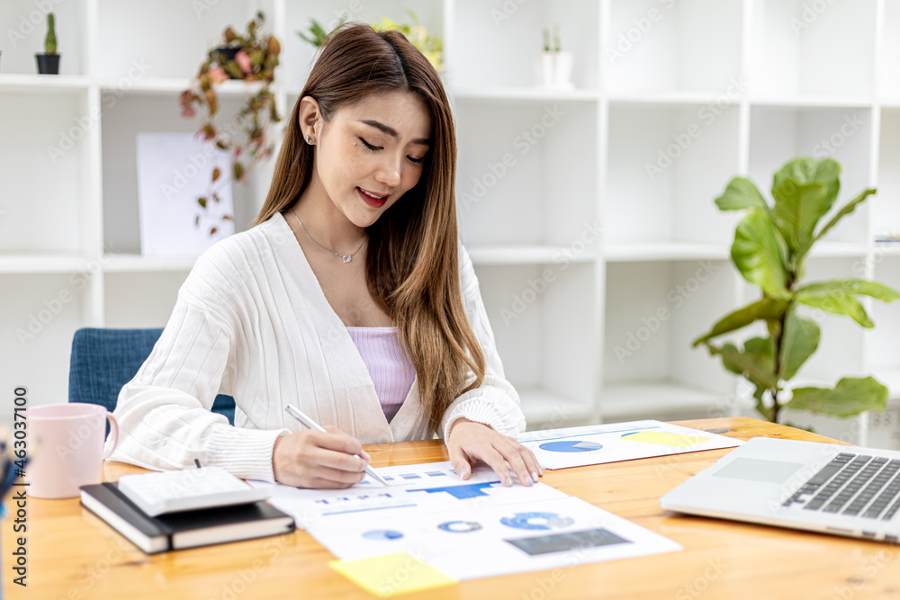 A beautiful Asian businesswoman sitting in her private office, she is checking company financial documents, she is a female executive of a startup company. Concept of financial management. A beautiful Asian businesswoman sitting in her private office, she is checking company financial documents, she is a female executive of a startup company. Concept of financial management.