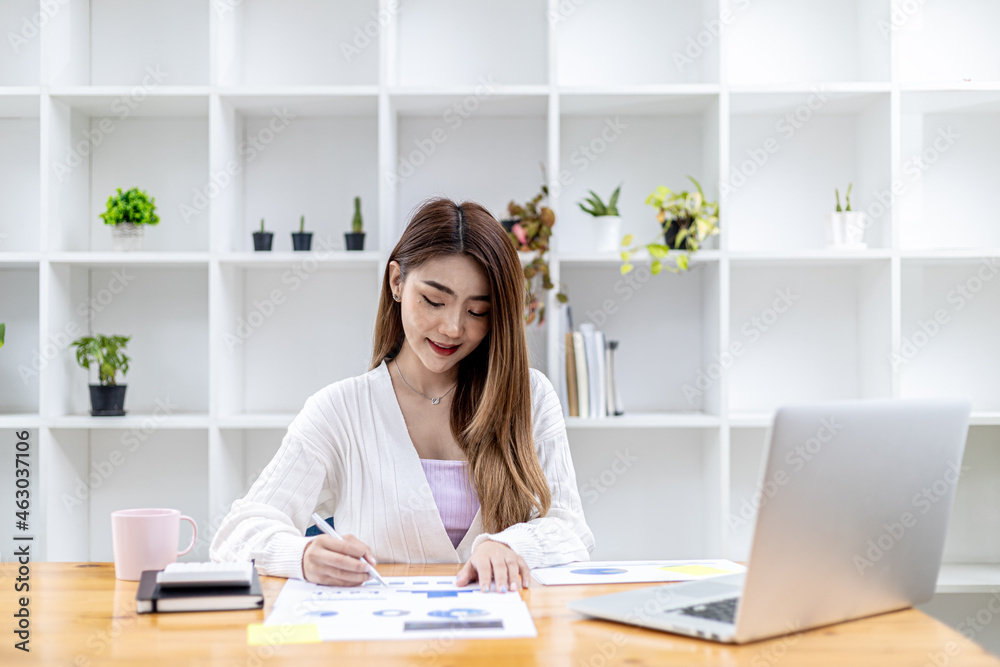 A beautiful Asian businesswoman sitting in her private office, she is checking company financial documents, she is a female executive of a startup company. Concept of financial management. A beautiful Asian businesswoman sitting in her private office, she is checking company financial documents, she is a female executive of a startup company. Concept of financial management.
