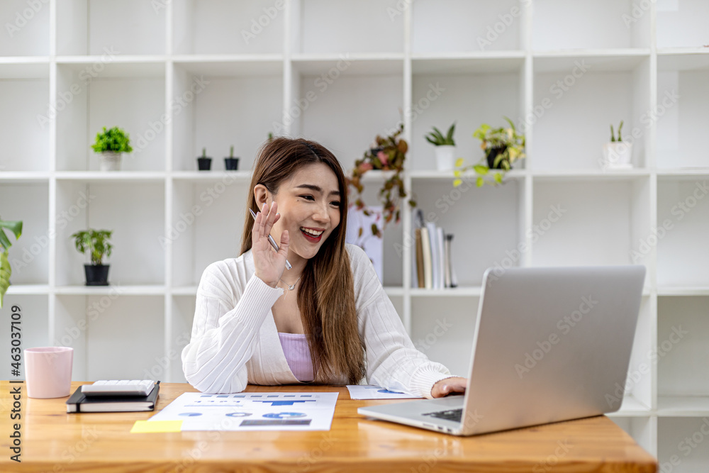 Beautiful Asian businesswoman sitting in her private office, she is talking to her partner via video call on her laptop, she is a female executive of a startup company. Concept of financial management Beautiful Asian businesswoman sitting in her private office, she is talking to her partner via video call on her laptop, she is a female executive of a startup company. Concept of financial management
